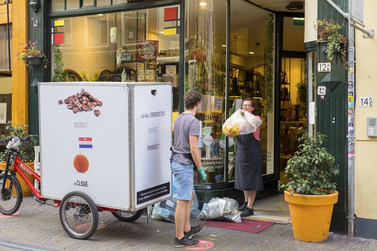 Two people work in the center of Utrecht. The man is collecting garbage from the woman's shop. Raw materials are made from the waste.