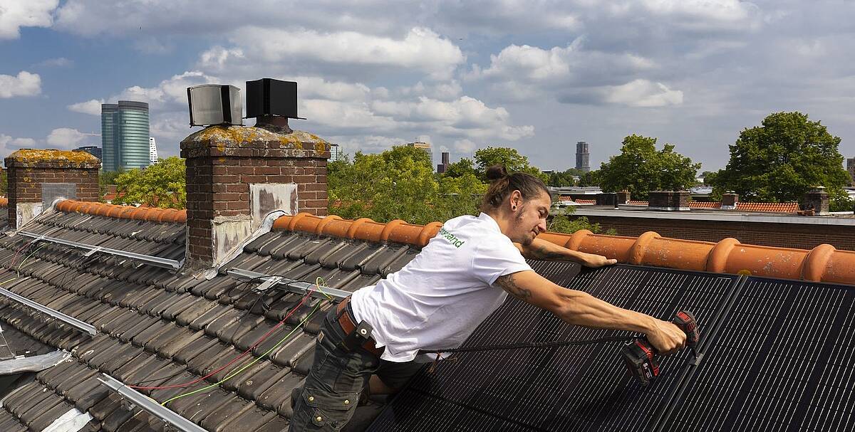 Installer installs solar panels on the roof of a house in Utrecht.